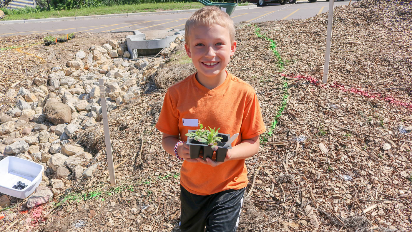 Smiling boy holding a plant.