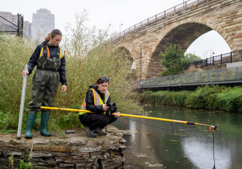 MWMO monitoring team staff conducting water quality testing near the Stone Arch Bridge.